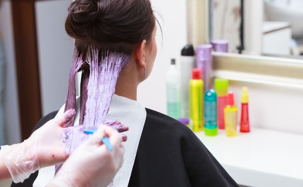 hairdresser applying color female customer at salon, doing hair dye